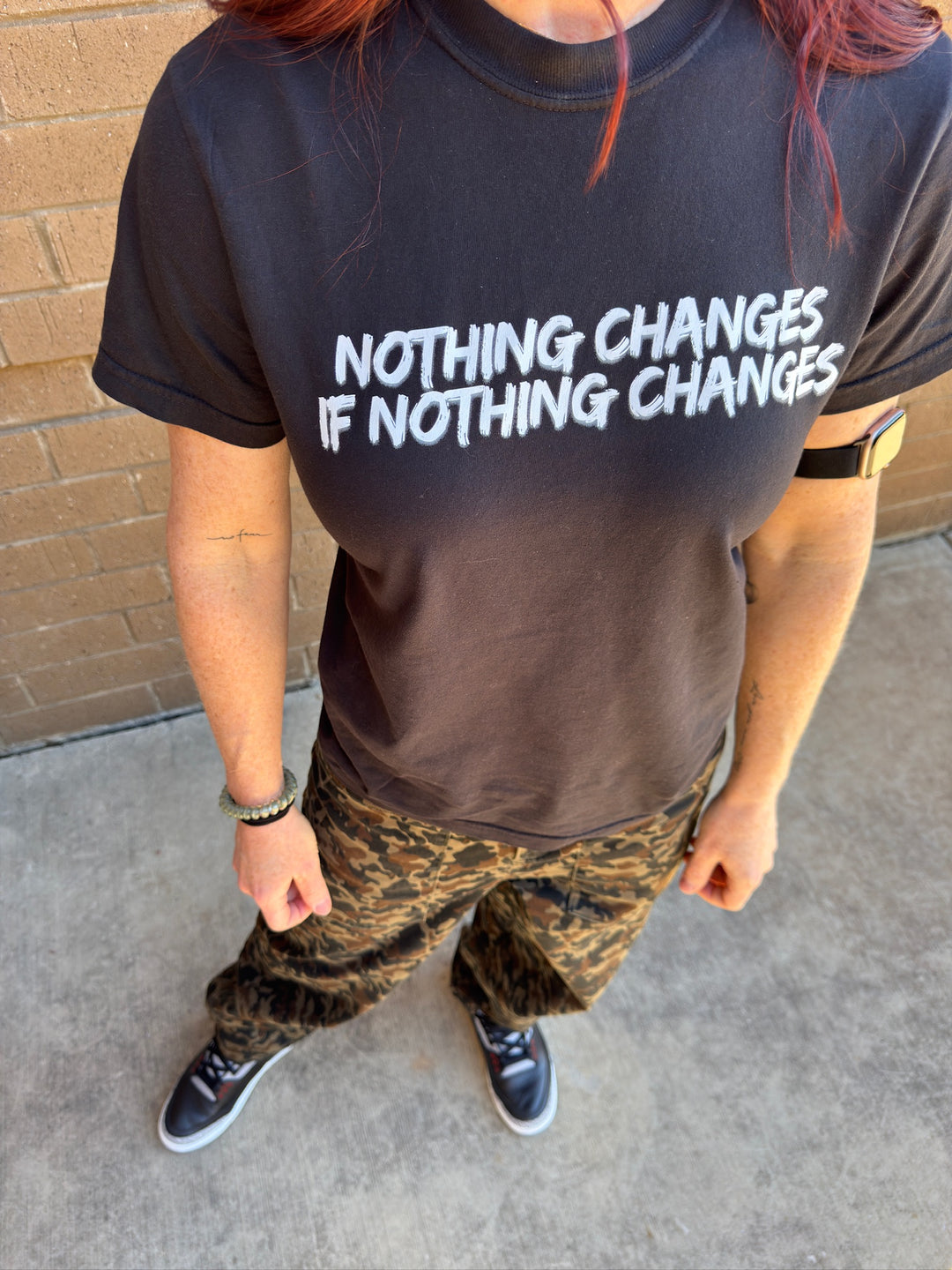 Dr. Betsy Grunch (Ladyspinedoc) wearing the "Nothing Changes If Nothing Changes" black tee shirt and her Ladyspinedoc Adjustable Bicep Smartwatch Band on her left arm. 