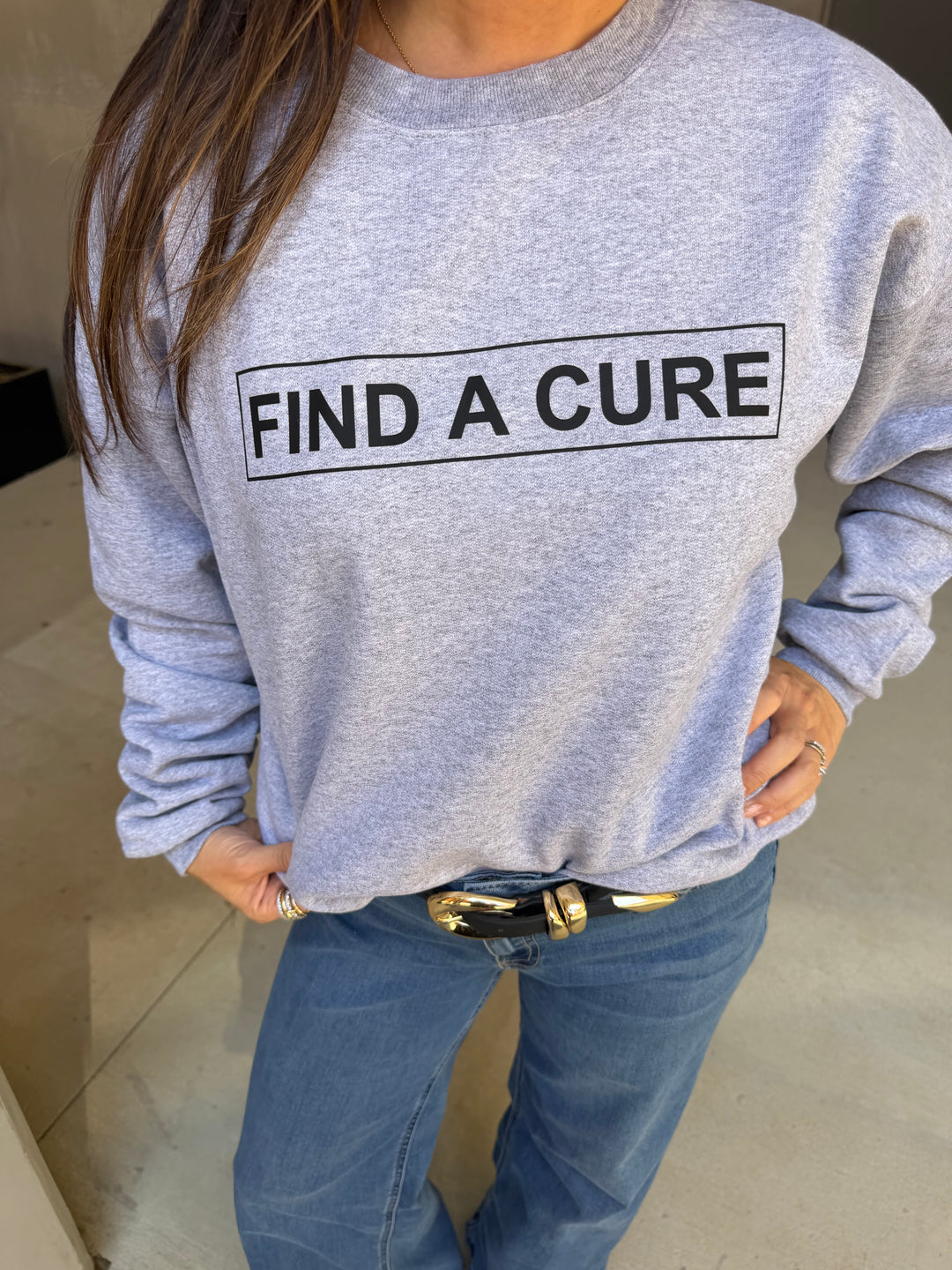 Person wearing a gray sweatshirt with 'Find a Cure' text, standing against a neutral background.