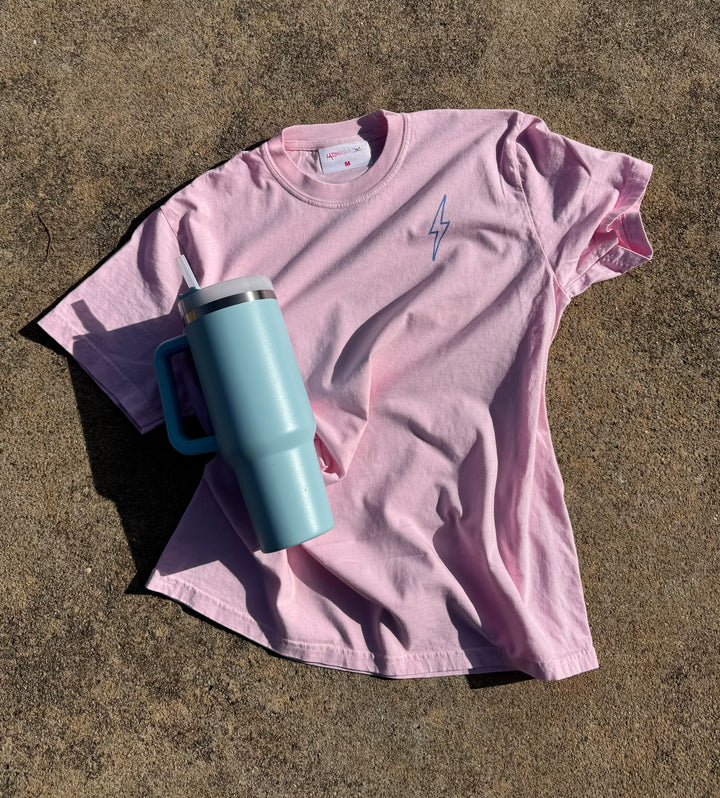 Flay lay of the front of the light pink lumbar puncture tee showing the Ladyspinedoc signature lightning bolt on upper left chest. 