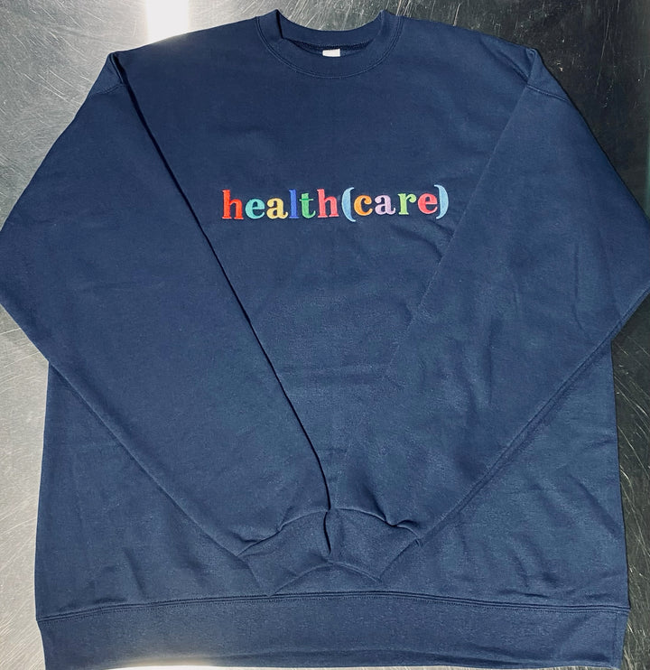 Blue sweatshirt with 'health(care)' text in multicolor on a metallic surface