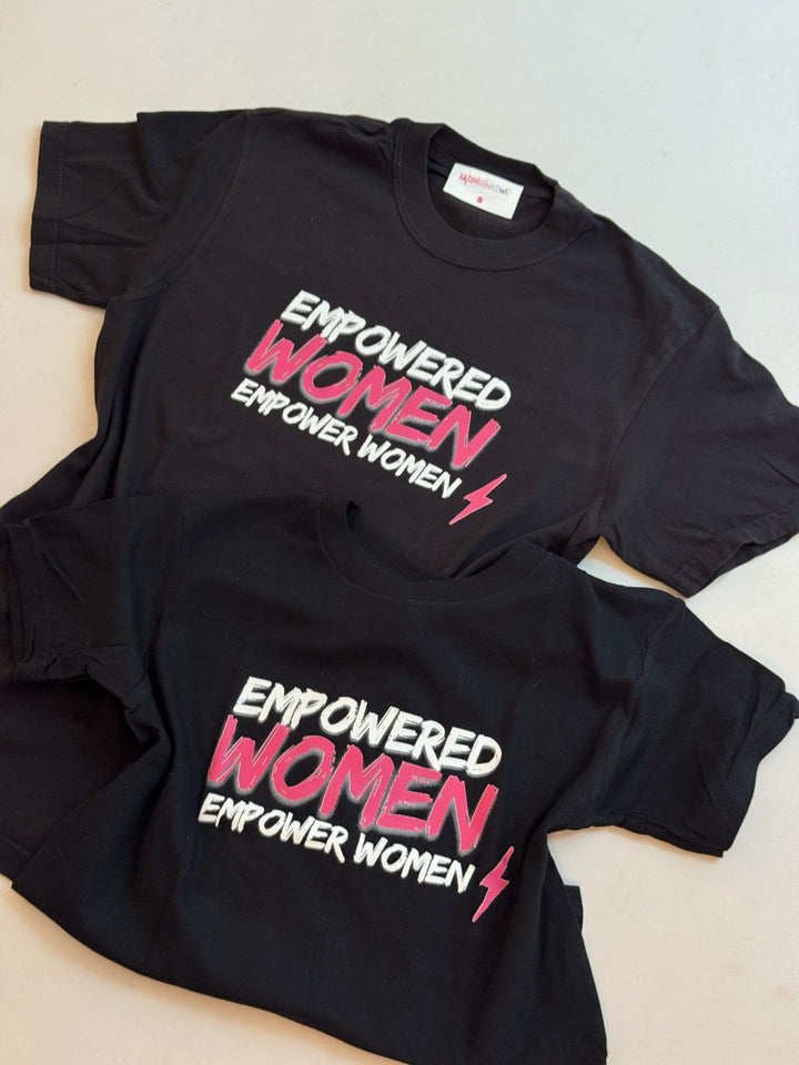 Two black Empowered Women tees on the floor