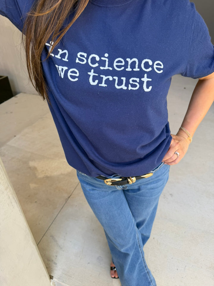 Person wearing a blue t-shirt with 'In science we trust' text.