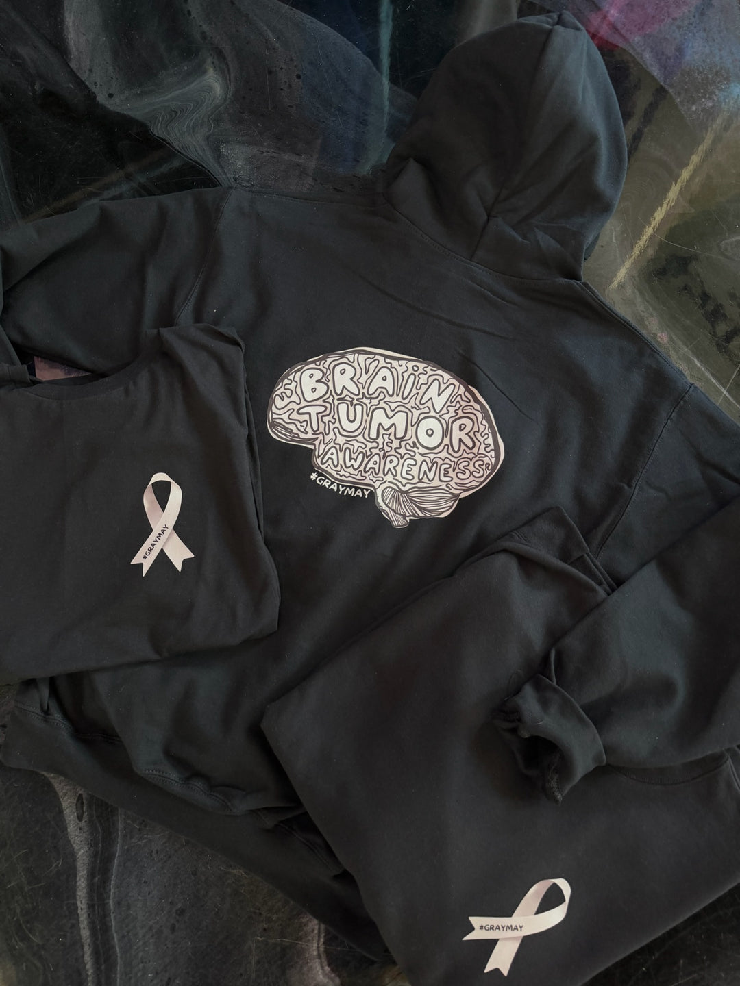 Black hoodie with brain tumor awareness design on a dark background