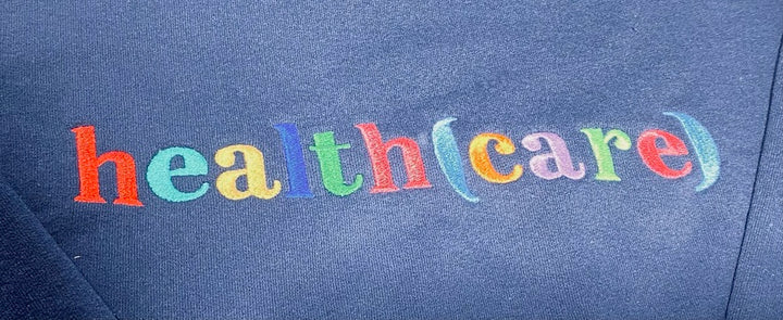 Colorful text 'health (care)' on a blue sweatshirt