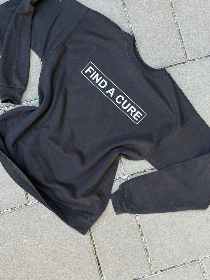 Black sweatshirt with 'Find a Cure' text on a tiled floor