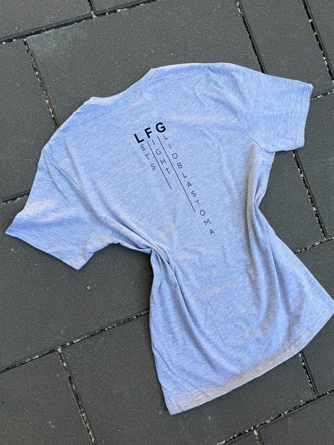 Gray t-shirt with 'LFG' text on a dark tiled floor