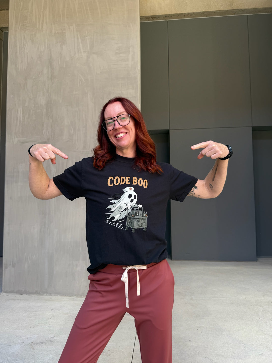Ladyspinedoc wearing a black t-shirt with 'CODE BOO' design, standing outdoors.