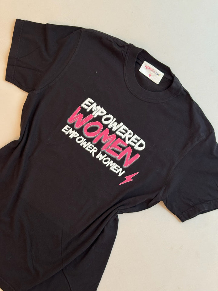 Black short sleeve tee shirt with white and pink text 'EMPOWERED WOMEN EMPOWER WOMEN' and a lightning bolt graphic.