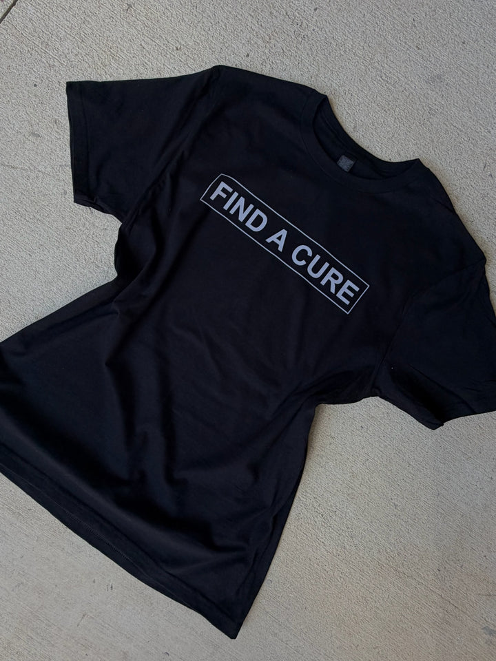 Black t-shirt with 'Find a Cure' text on a gray surface