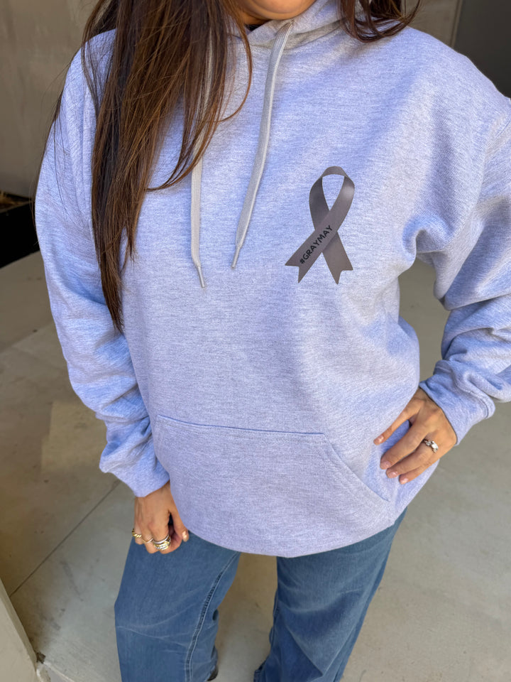 Person wearing a gray hoodie with a gray ribbon design on a neutral background