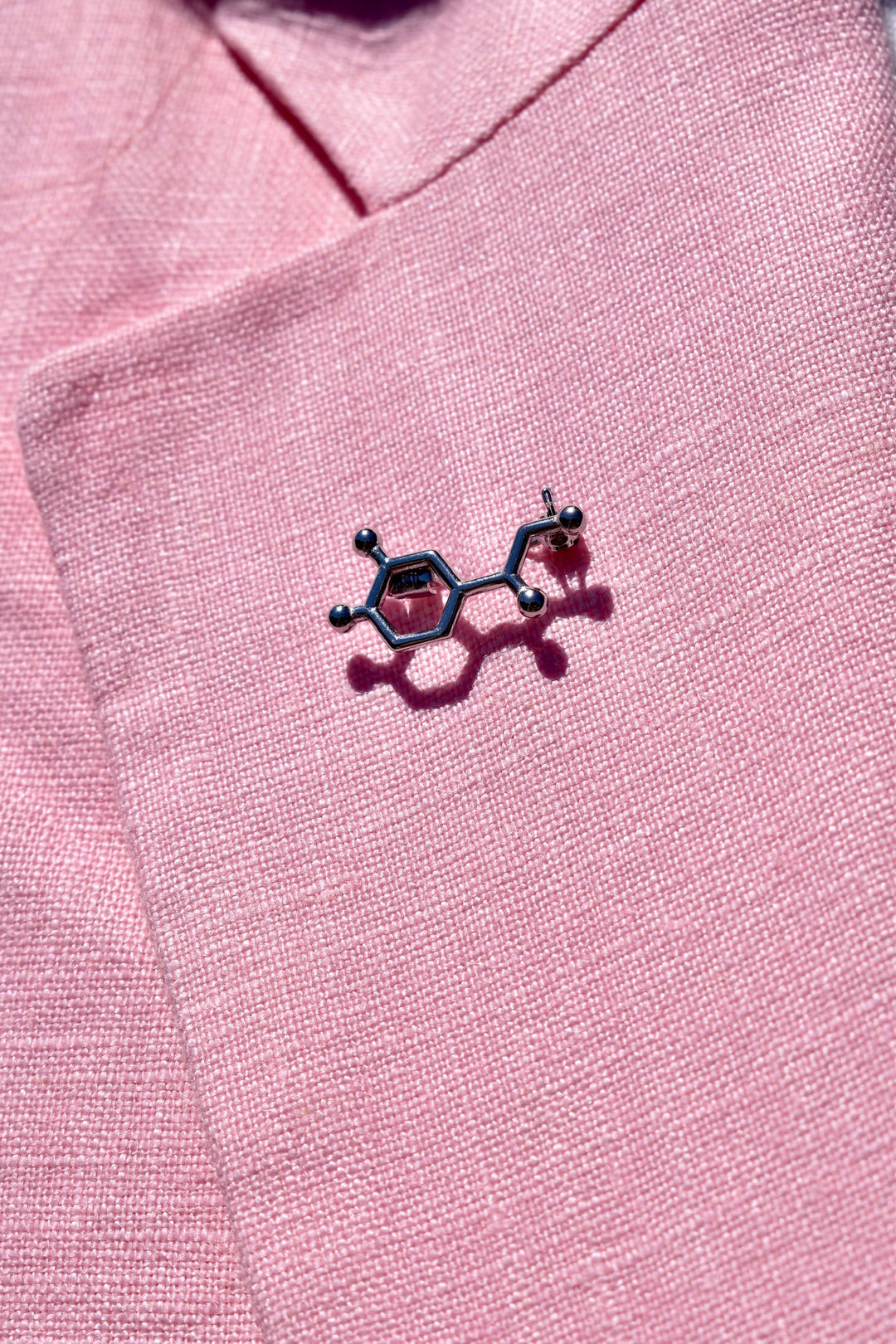 Close up of Noradrenaline Molecule Lapel Pin on pink lapel