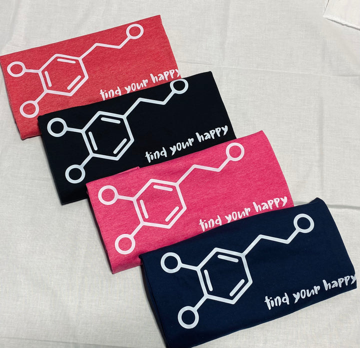 Four folded t-shirts with molecular design and 'find your happy' text on a light gray background