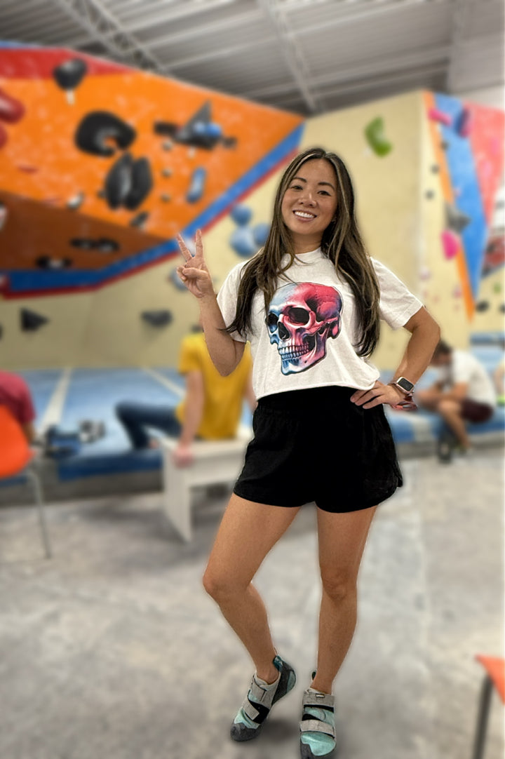 Model wearing the Skull Style Cropped Tee – White Short Sleeve Crop Top with Skull Design at a rock climbing facility