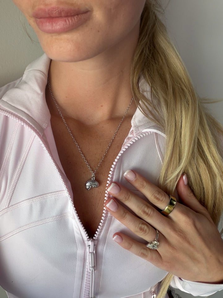 Person wearing a silver necklace with a brain pendant, wearing a white jacket.