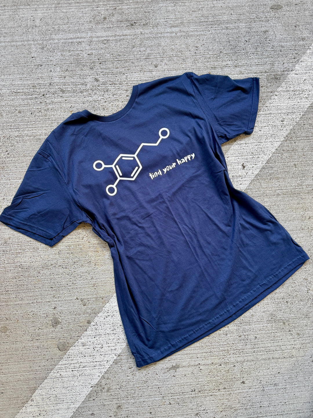 Blue t-shirt with a white dopamine molecule graphic design on a concrete surface