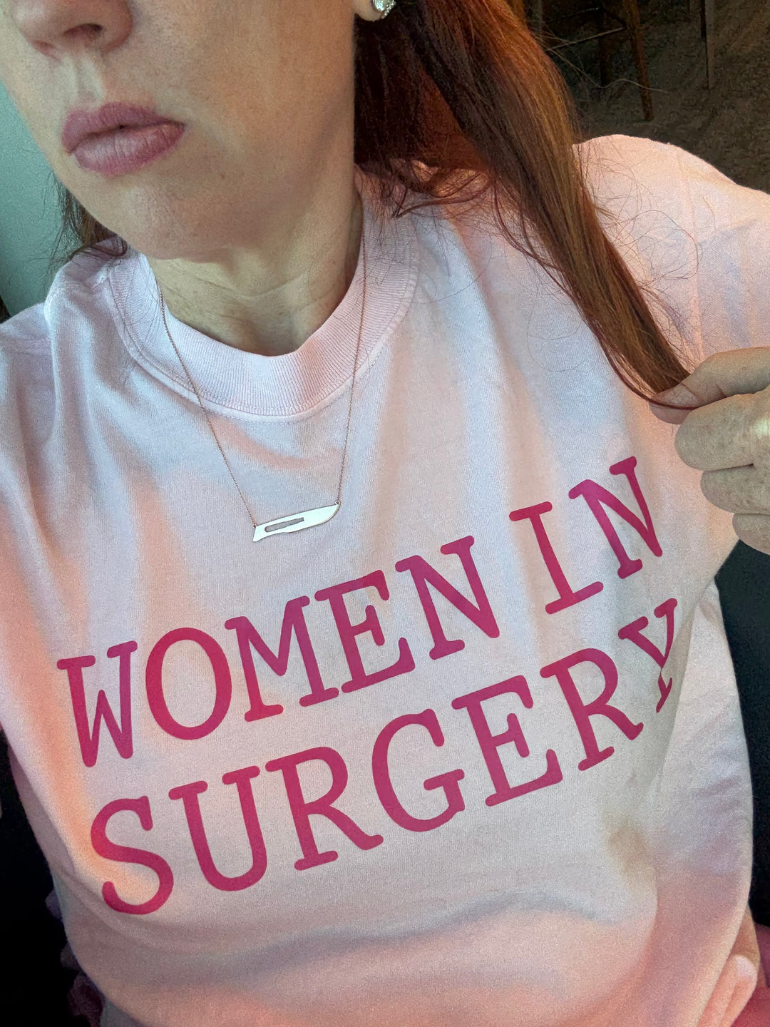 Dr. Grunch wearing a light pink shirt with 'WOMEN IN SURGERY' printed in pink text.