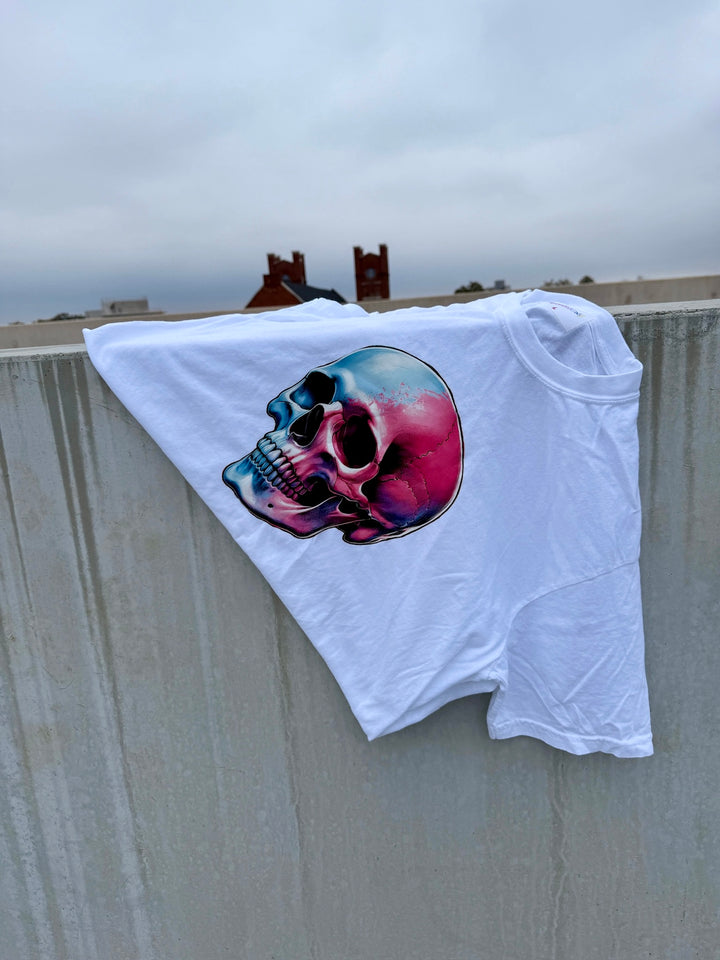 Skull Style Cropped Tee – White Short Sleeve Crop Top with Skull Design draped on concrete wall