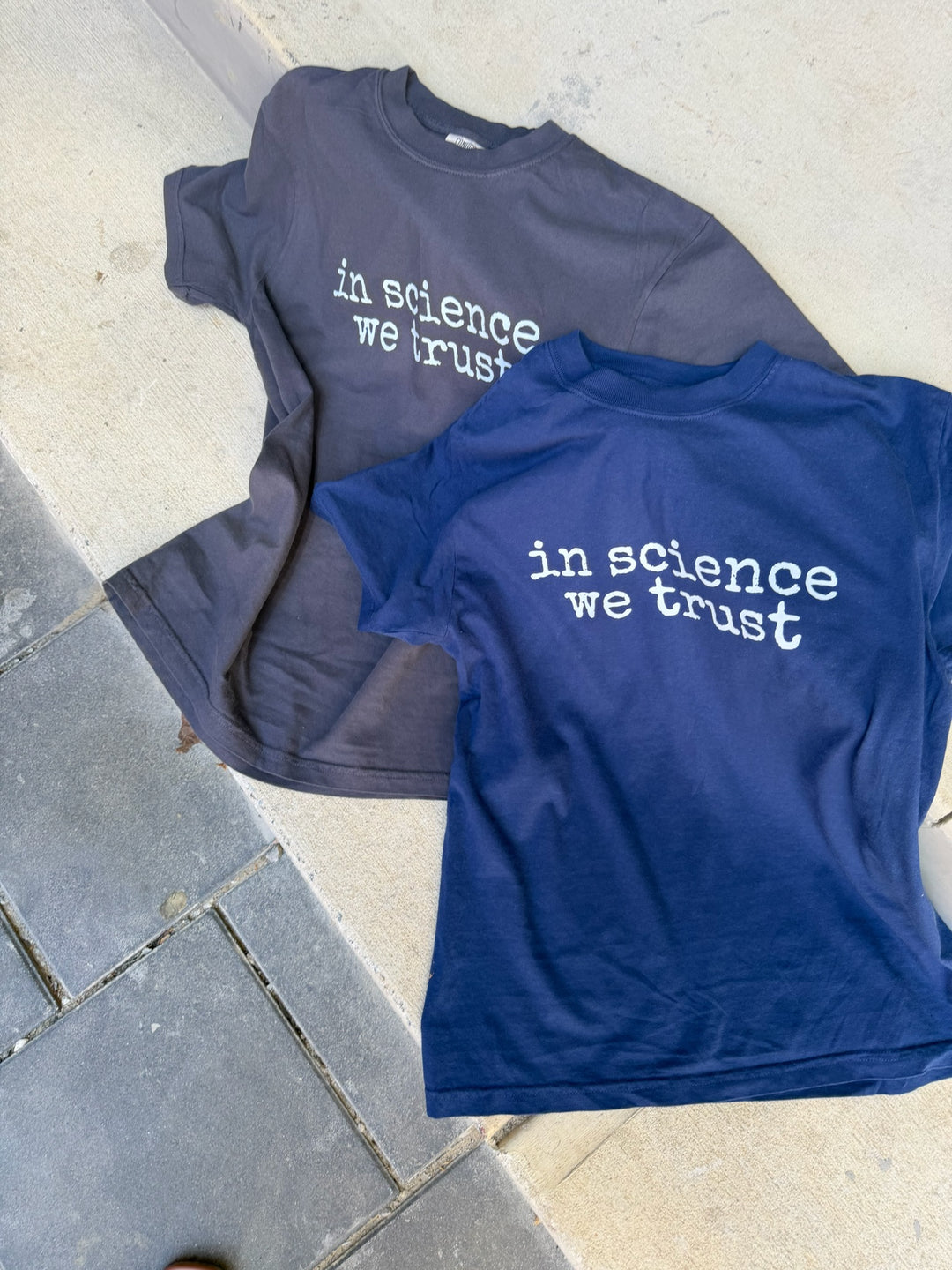 navy shirt and dark gray shirt with the phrase in science we trust (in white) on it