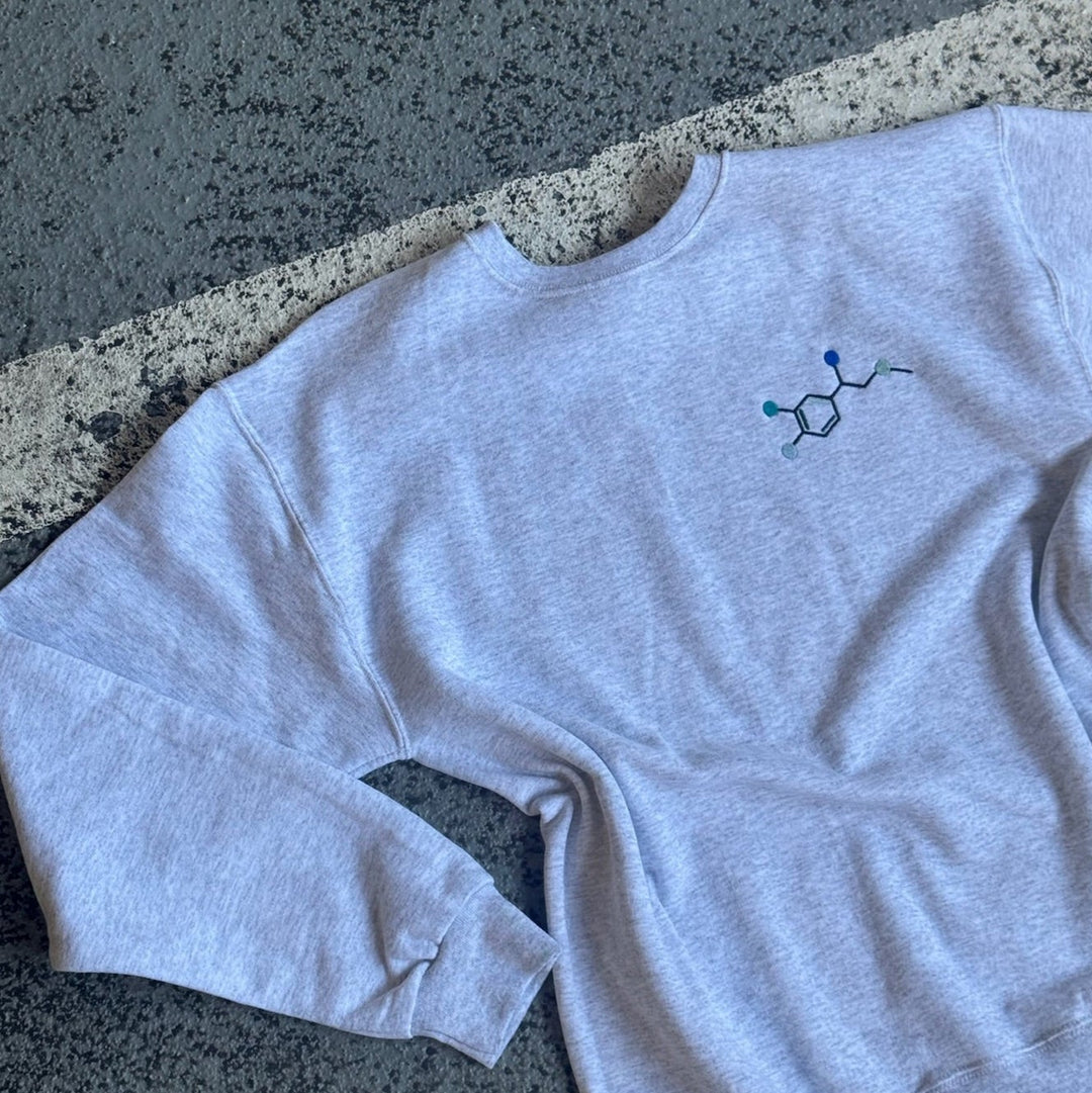 Flat lay on pavement of Ladyspinedoc Code Cart Crewneck Sweatshirt - Gray Shirt with Embroidered Epinephrine (Adrenaline) Molecule Design
