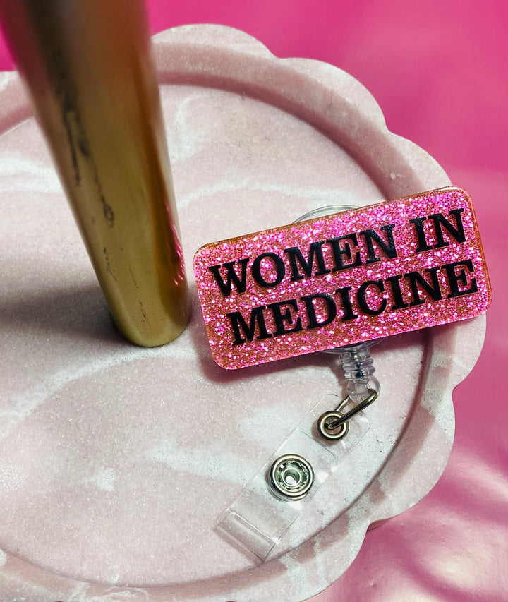 Pink glittery badge holder with 'WOMEN IN MEDICINE' text on a pink background