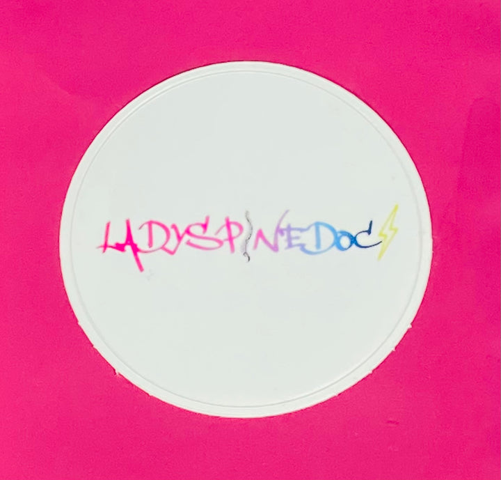 Circular white sticker with colorful Ladyspinedoc text on a pink background
