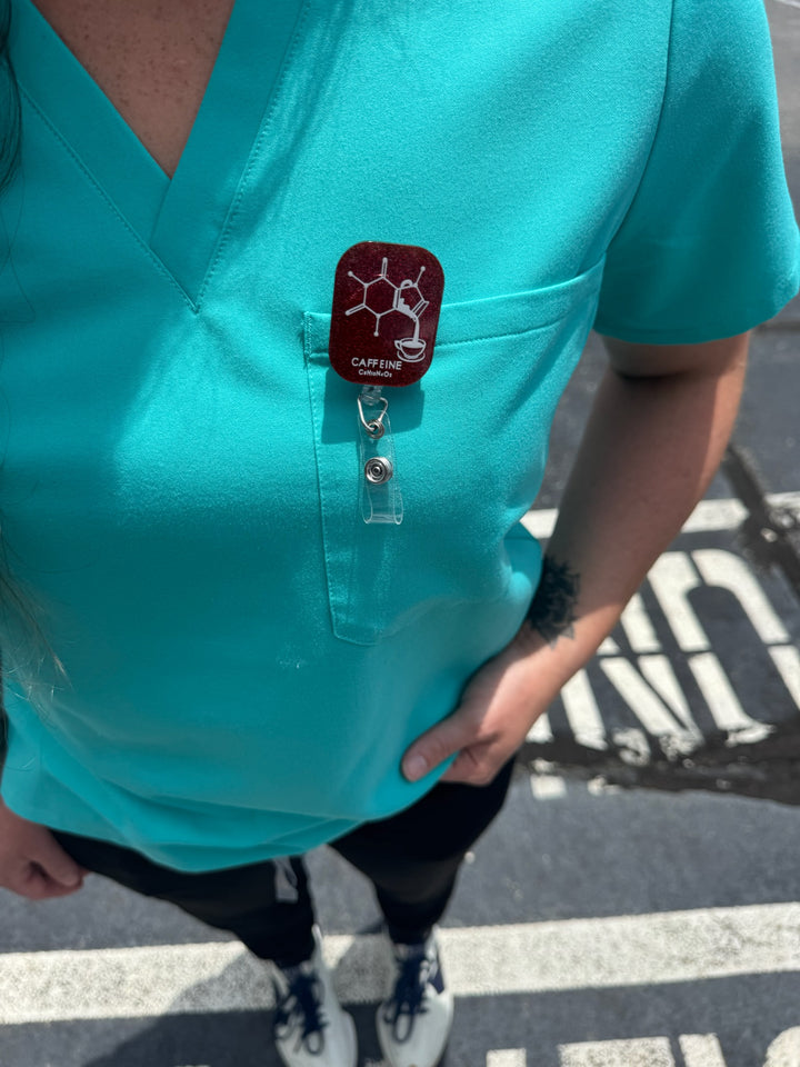 Woman wearing Ladyspinedoc Sparkly Red Enerjava Badge Reel clipped to front pocket of scrub shirt