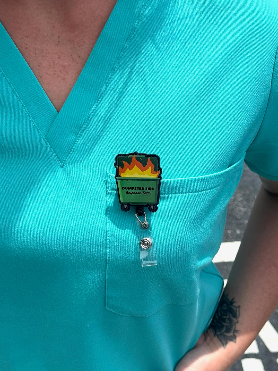 Woman wearing Ladyspinedoc Dumpster Fire Response Team Badge Reel on front pocket of scrubs