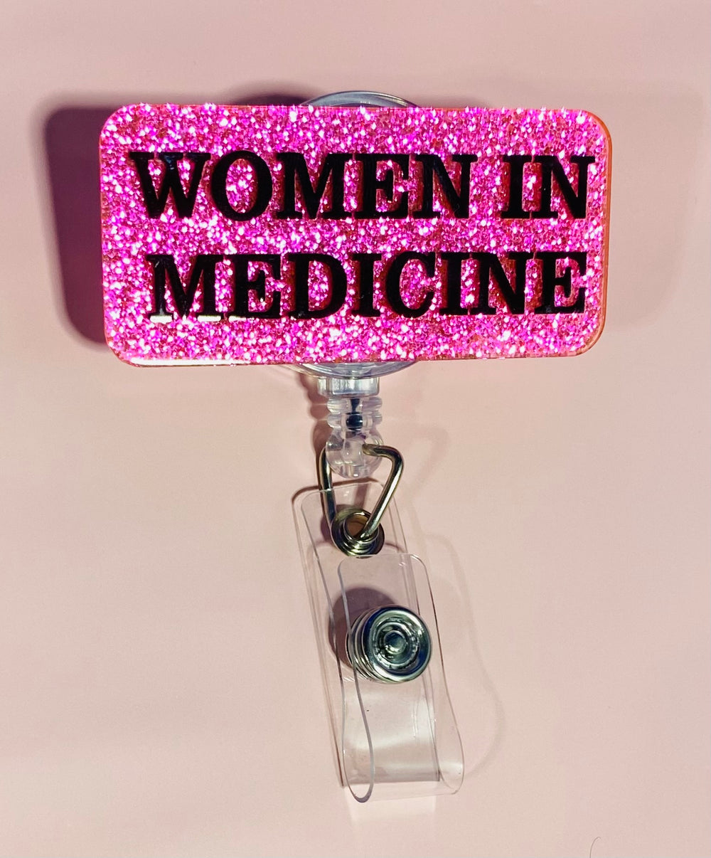 Pink glitter badge holder with 'WOMEN IN MEDICINE' text on a beige background
