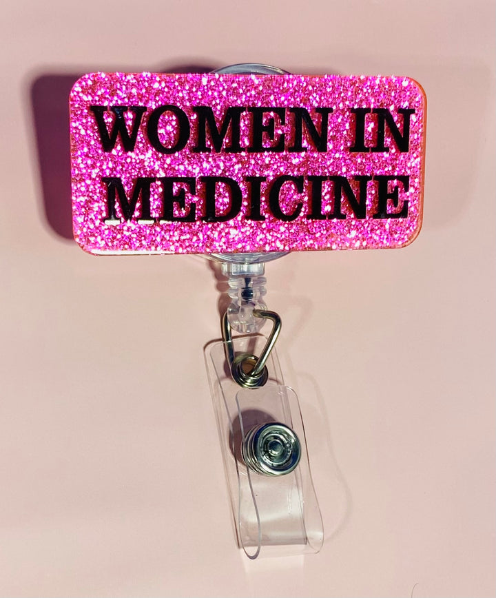 Pink glitter badge holder with 'WOMEN IN MEDICINE' text on a beige background